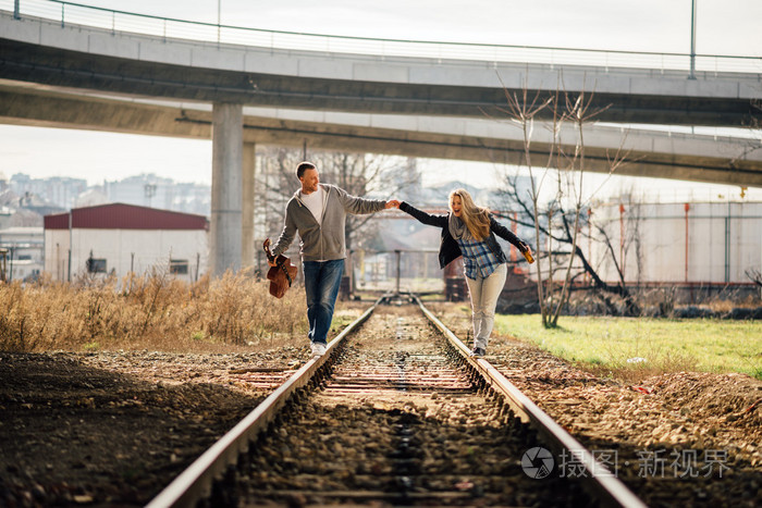 一对夫妇男孩和女孩在铁路上行走与吉他和啤酒