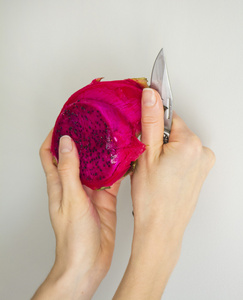 明亮的紫罗兰红皮肤紫果肉的水果.女人的手,用刀在剥离过程照片