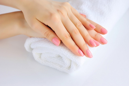 一个女人与粉红色指甲的手在一条毛巾
