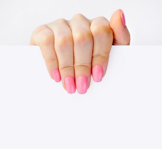 一个女人抱着白空纸的粉红色指甲的手