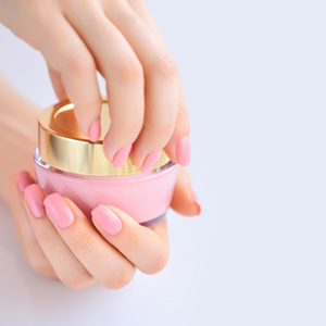 一个女人与奶油的粉红色指甲的手