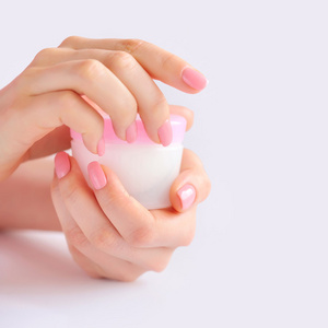 一个女人与奶油的粉红色指甲的手