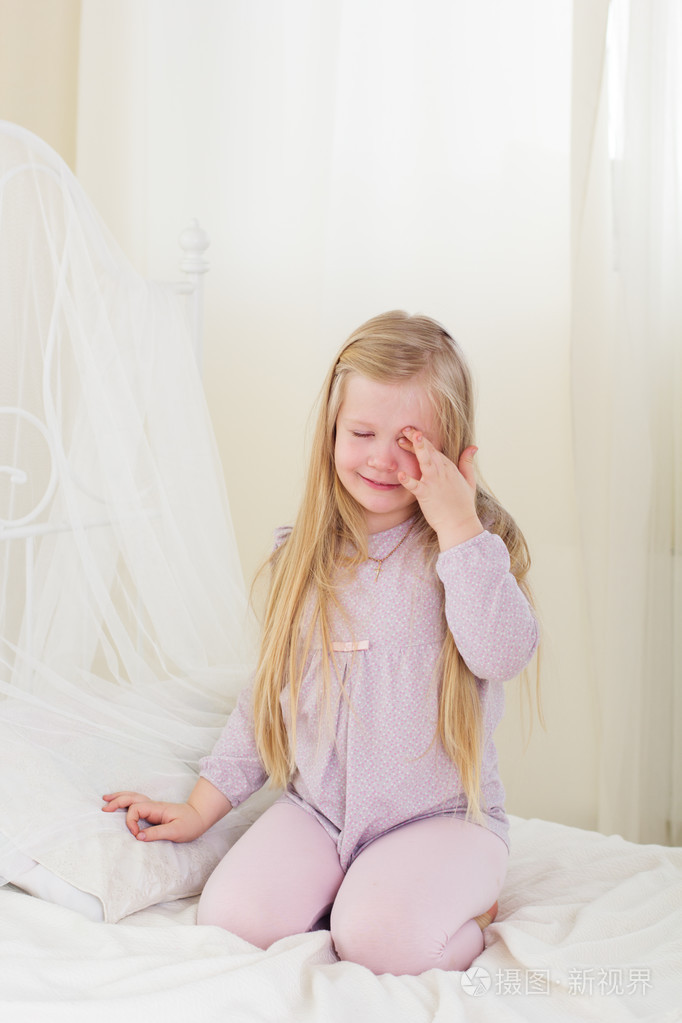 累了可爱的孩子女孩揉眼睛躺在床上