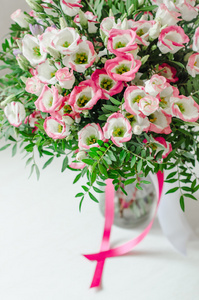 浪漫束美丽的粉红色和白色的桔梗花缎面带在白色背景上的一个花瓶