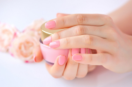 一个女人与奶油的粉红色指甲的手照片