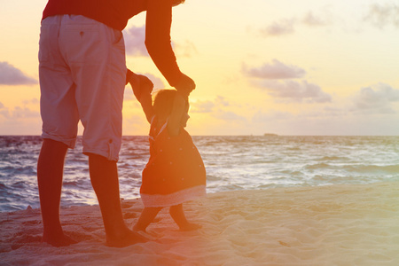 父亲和小女儿散步在日落时的剪影