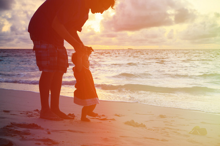 父亲和小女儿散步在日落时的剪影
