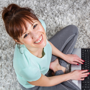 微笑女人在家里使用的便携式计算机