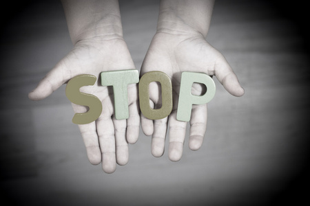 孩子请求帮助.手掌上的书面的停止字母照片