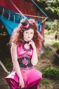 在滑稽设计师粉红色的衣服和戴着帽子，红头发的漂亮女孩是马戏团在幕后。小丑。马戏团的帐篷