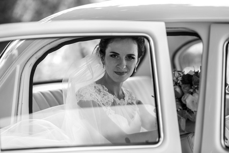 美丽的黑发新娘在车中微笑
