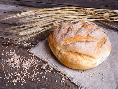 自制的面包和成熟的麦穗小麦上木制的背景
