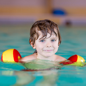 swimmies 学习在室内游泳池游泳的小小孩男孩