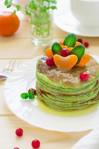 绿色煎饼与菠菜和香蕉装饰柑橘 薄荷和小红莓