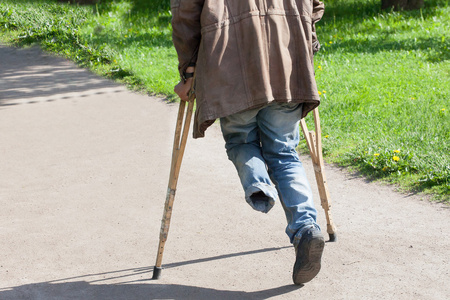 独腿残疾人用拐杖走在公园里