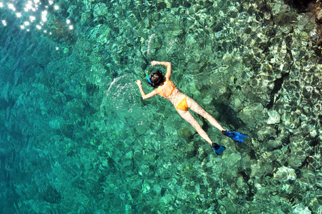 年轻女子在透明的浅海浮潜