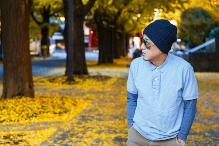 亚洲人在马球 t 恤走在一条街道在秋天