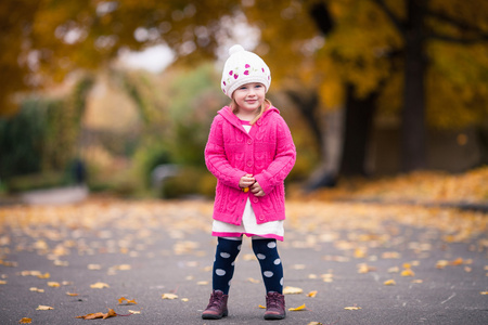 在明亮的衣服的小女孩站在秋天的花园里
