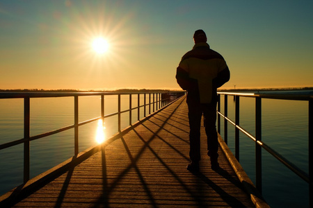 人剪影步行到太阳神奇早上海面之上的码头建设