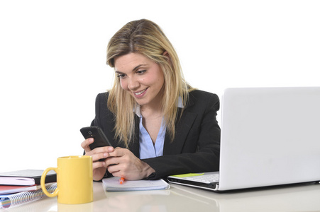 幸福的白种人金发碧眼业务女人工作在办公室电脑桌使用手机