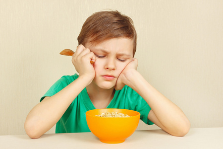 小不满的男孩不想吃麦片粥照片