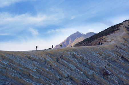 游客和矿工走在 Ijen 火山在东爪哇，载有世界上最大的酸性火山火山湖，被称为卡瓦 Ijen，喷出硫磺的烟雾在早晨