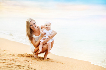 快乐妈妈和小女孩坐在海边的沙滩上