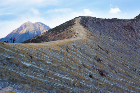 游客和矿工走在 Ijen 火山在东爪哇，载有世界上最大的酸性火山火山湖，被称为卡瓦 Ijen，喷出硫磺的烟雾在早晨