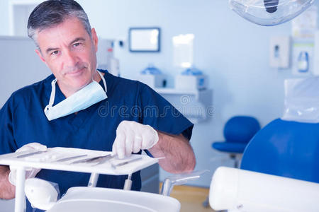 牙医拿起工具，对着相机微笑