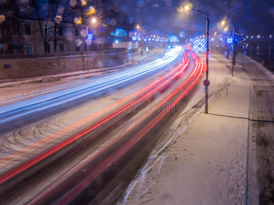 雪中的冬天，冰路上的汽车夜间亮着