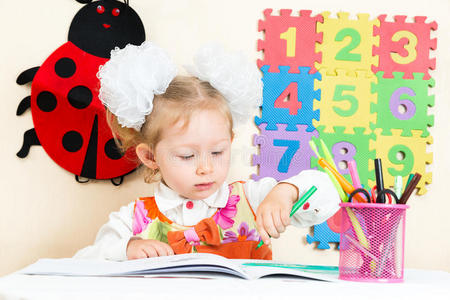 可爱的女孩在幼儿园的桌子上用彩色铅笔画画
