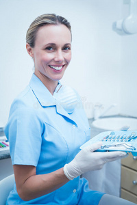 穿着蓝色擦洗器的女牙医拿着工具托盘