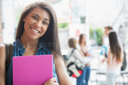 漂亮的学生微笑着拿着记事本