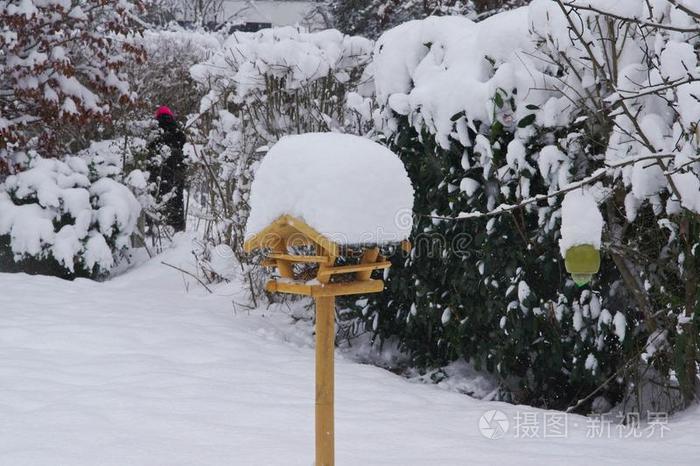 屋顶上有很多雪的喂鸟器