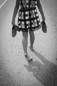 赤脚走在沥青路面上的女孩
