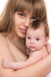 美丽微笑的年轻的母亲抱着一个婴儿的肖像