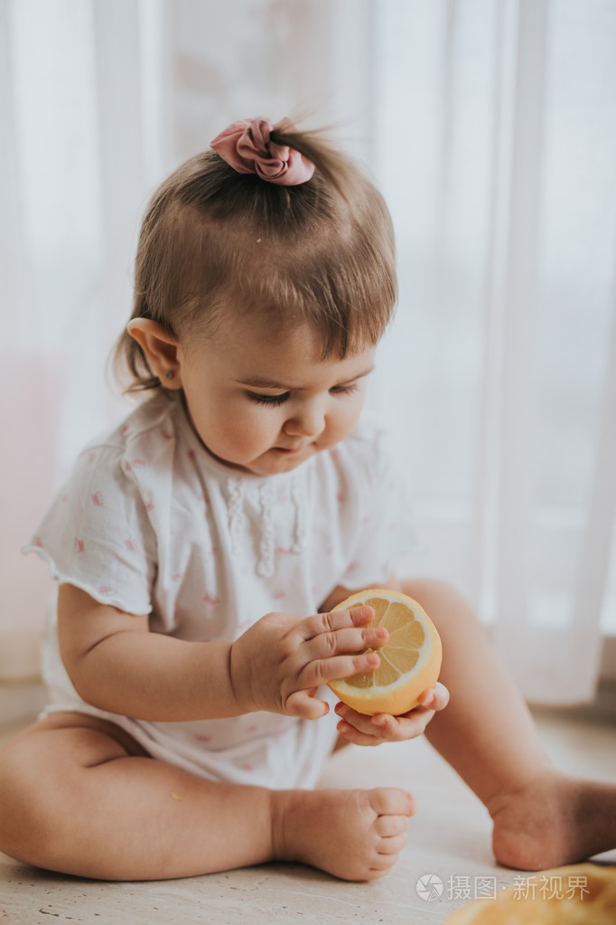 可爱的小宝贝女孩在厨房的桌子上吃柑橘类水果富含维生素和滑稽可爱的
