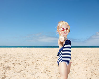 条纹泳衣现身拇指的白色海滩上的女孩