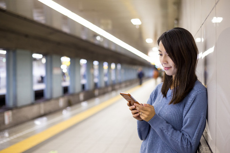 女人在火车平台上使用智能手机图片