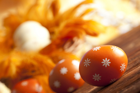 橙色复活节彩蛋和木制的桌子上的羽毛
