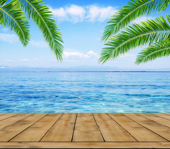 蓝色的大海 棕榈树叶和木质的露台