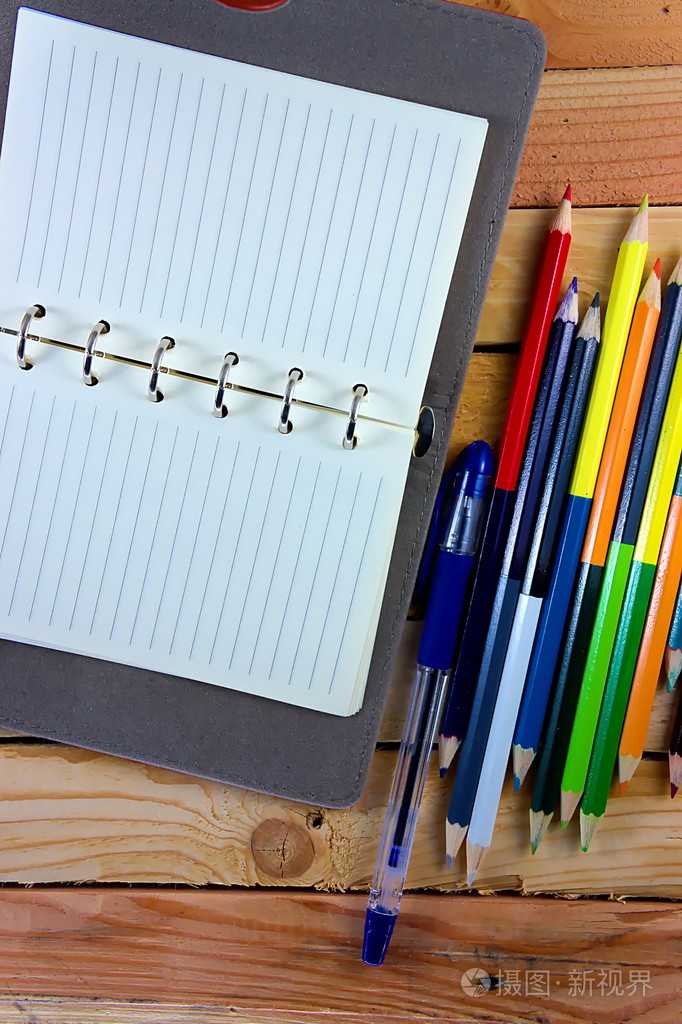 在顶视图上看到的颜色铅笔和笔记本木制的桌子上
