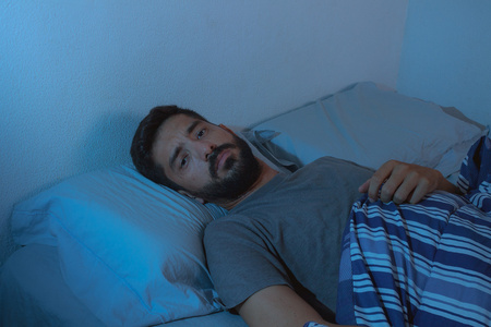 睡眠障碍,失眠.小胡子男人躺在床上醒着照片