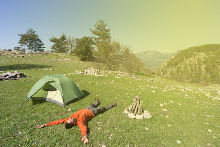 在夏天在晴朗的一天带个帐篷在山上露营的人
