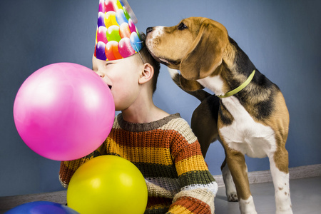 在庆祝的帽，拿着五颜六色的气球男孩