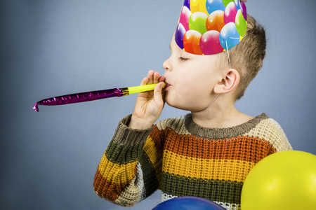 在庆祝的帽，拿着五颜六色的气球男孩