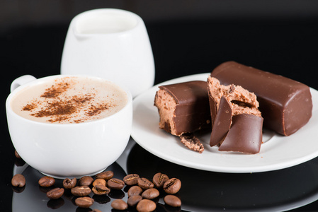 一杯卡布奇诺咖啡和巧克力的釉面的豆腐蛋糕上黑八