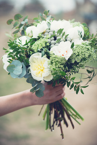 婚礼花束特写镜头，美丽温柔婚礼花束的混合花和新娘的手
