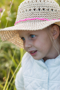 在花园里的一顶帽子的金发女孩微笑着阳光灿烂的夏天的一天