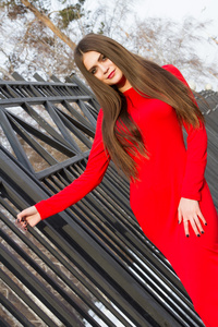 年轻女孩穿着红色斜靠金属围栏